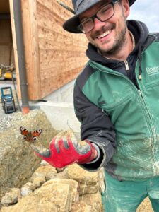 Schmetterling sitzt auf der Hand eines Mitarbeiters während Arbeiten an einer naturnahen Fläche