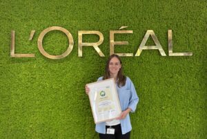 Ina Allmendinger hält die Urkunde des Biodiversitätspreises für die Wirtschaft vor einer begrünten L’Oréal-Wand.