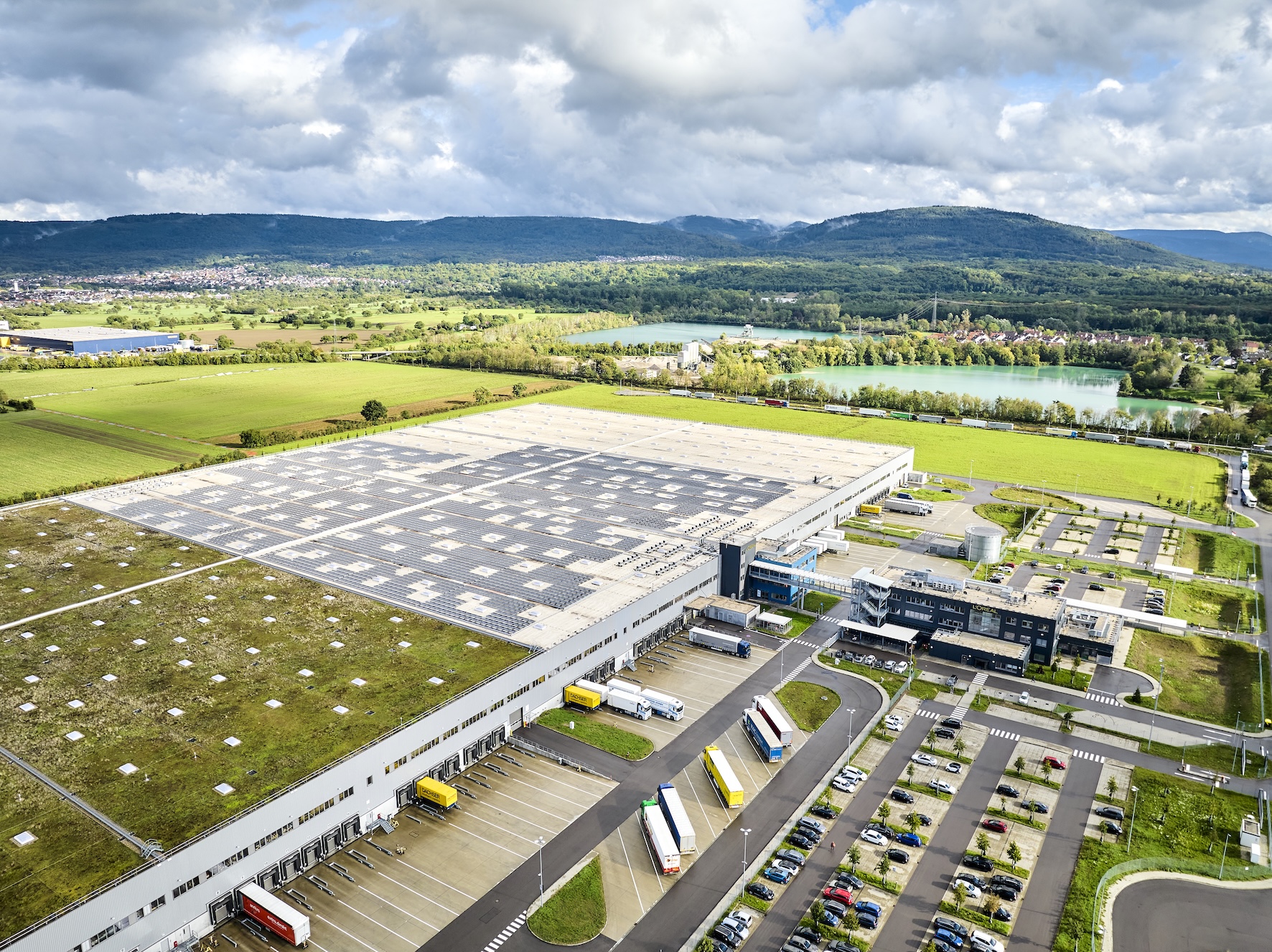 Luftaufnahme des L’Oréal-Logistikzentrums Muggensturm mit großem Gründach und umliegender Landschaft.